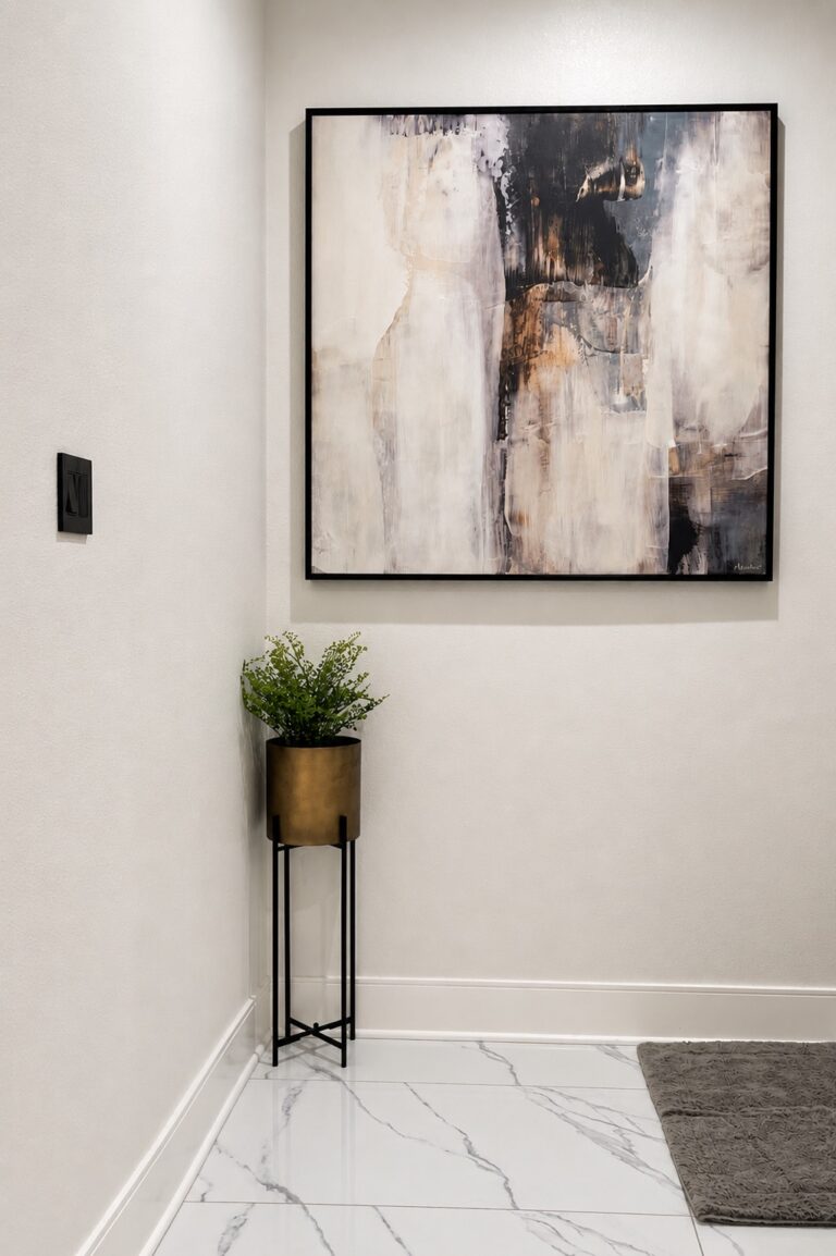 Dark charcoal vertical fluted accent wall styled with an abstract art frame and a fresh greenery planter to soften the bathroom vanity space by Emma's Interior in The Woodlands, TX