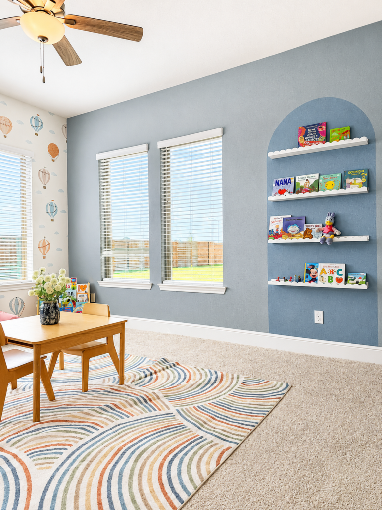 Arched accent wall painted blue with floating shelves for kids book storage by Emma’s Interior in The Woodlands, TX
