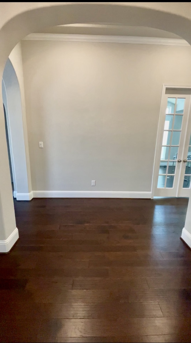 View from an open conversational sitting room looking back toward an empty narrow hallway entrance in Cypress, TX