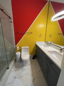 Before photo of a bathroom in The Woodlands, TX with bold red and yellow painted geometric walls and a dark gray vanity.
